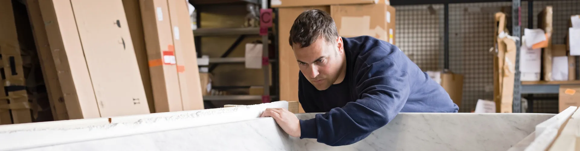 Anlagenmechaniker Sanitaer, Heizung und Klima prüft die Materialbeschaffenheit einer Badewanne.