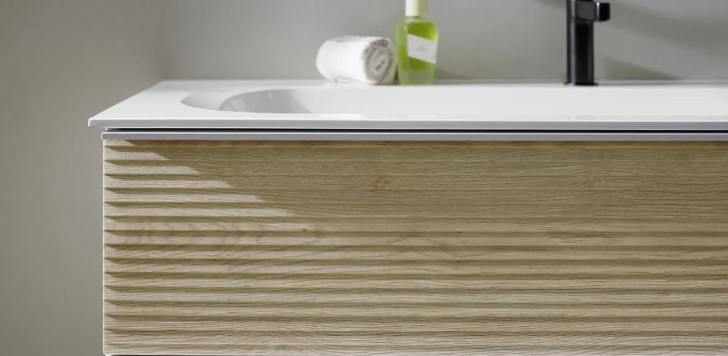 Nahaufnahme eines stilvollen Waschtisches der Marke burgbad Fiumo, der eine helle Holzschublade und eine klare weiße Oberfläche zeigt. 