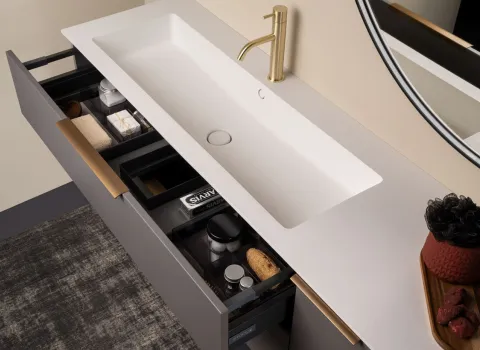Detail eines Stocco Waschtisches mit goldener Armatur, offenem Schubfach und organisiertem Innenleben.