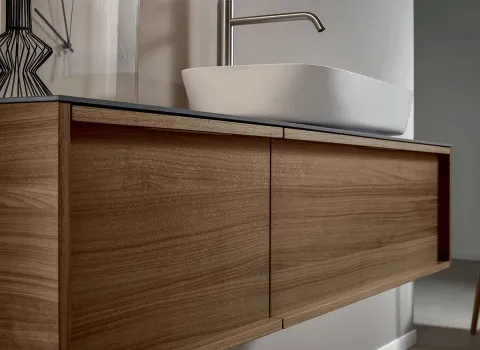 Detailansicht eines schwebenden Holzwaschtischs mit dunkler Platte und Aufsatzbecken von Stocco.