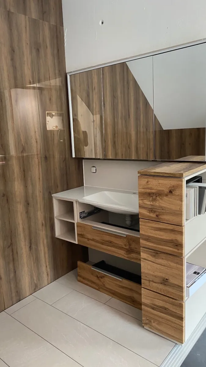 Ein modernes Badezimmermöbelset kombiniert weiße Oberflächen mit warmem Holzdekor in einem klar strukturierten Design.