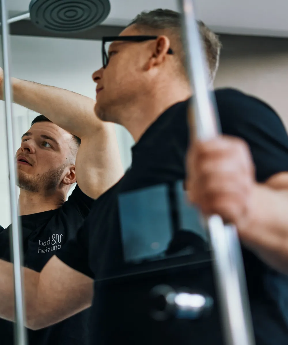 Anlagenmechaniker SHK montieren eine Duschtür.