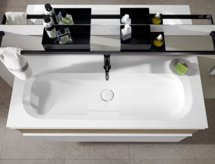 Von oben fotografiertes breites weißes Waschbecken Fiumo von burgbad und schwarzem Zubehör. 