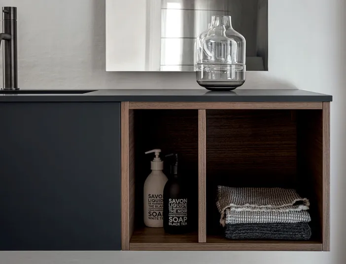 Detail eines Stocco Badmöbels mit dunkler Front, offener Holzablage und integrierter Waschtischplatte.