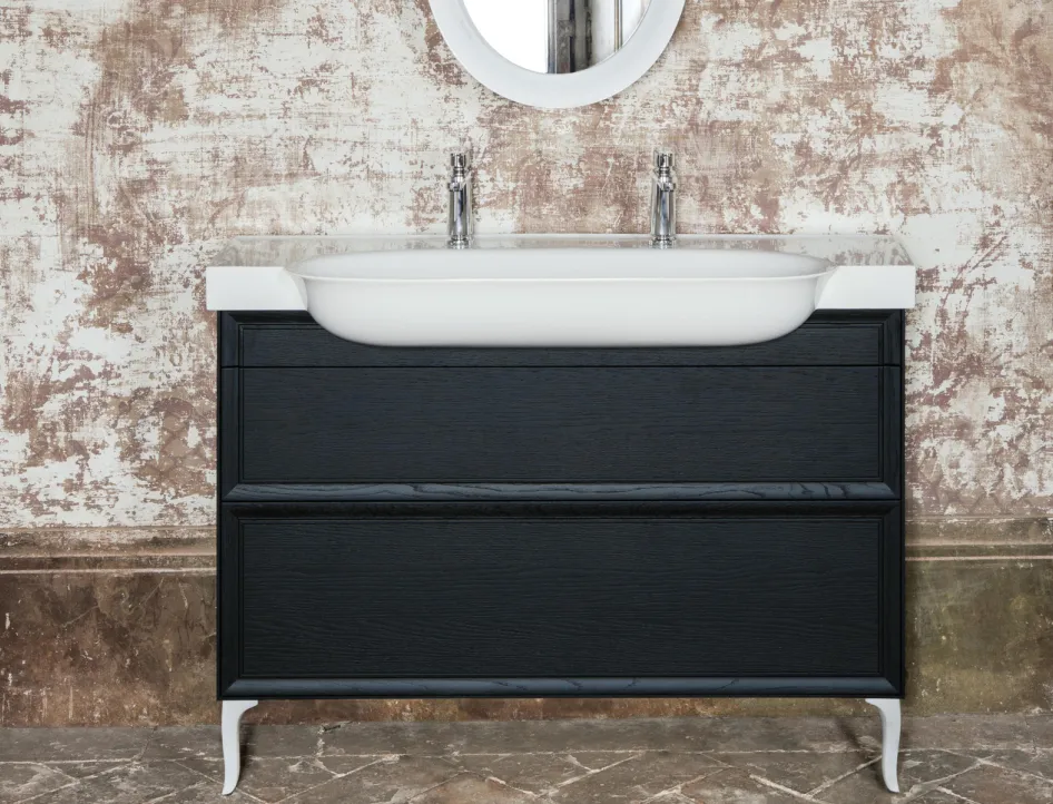 Ein eleganter, schwarzer Waschtisch mit geschwungenen, weißen Beinen steht vor einer antik anmutenden Wand mit verblasster, rustikaler Textur.